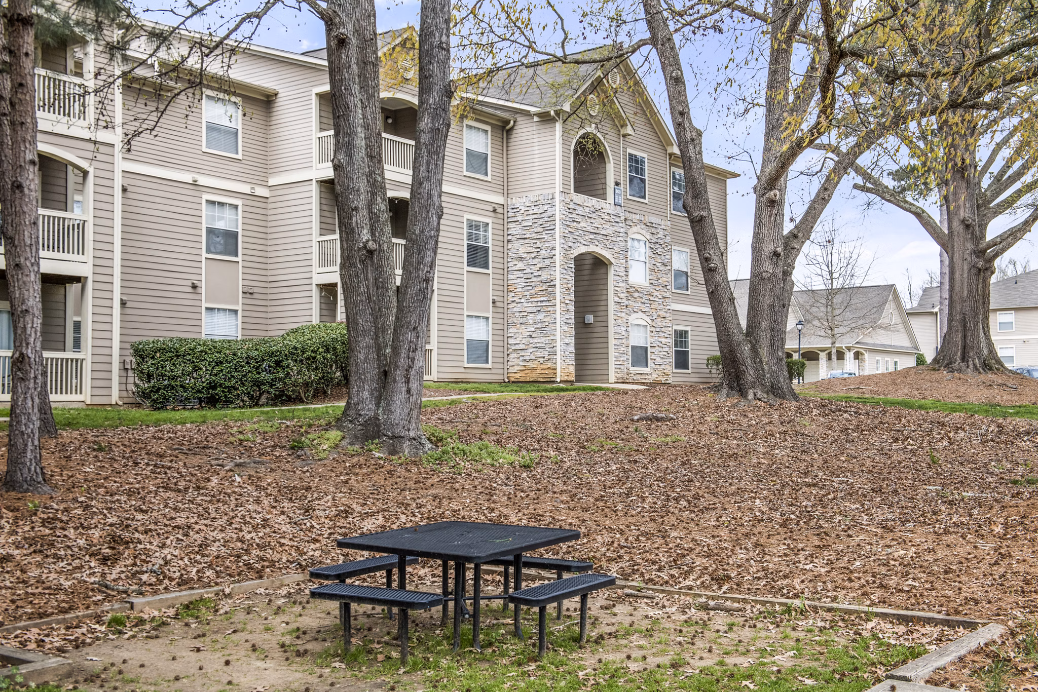 Scenic apartment building with a picnic table surrounded by trees and colorful autumn leaves