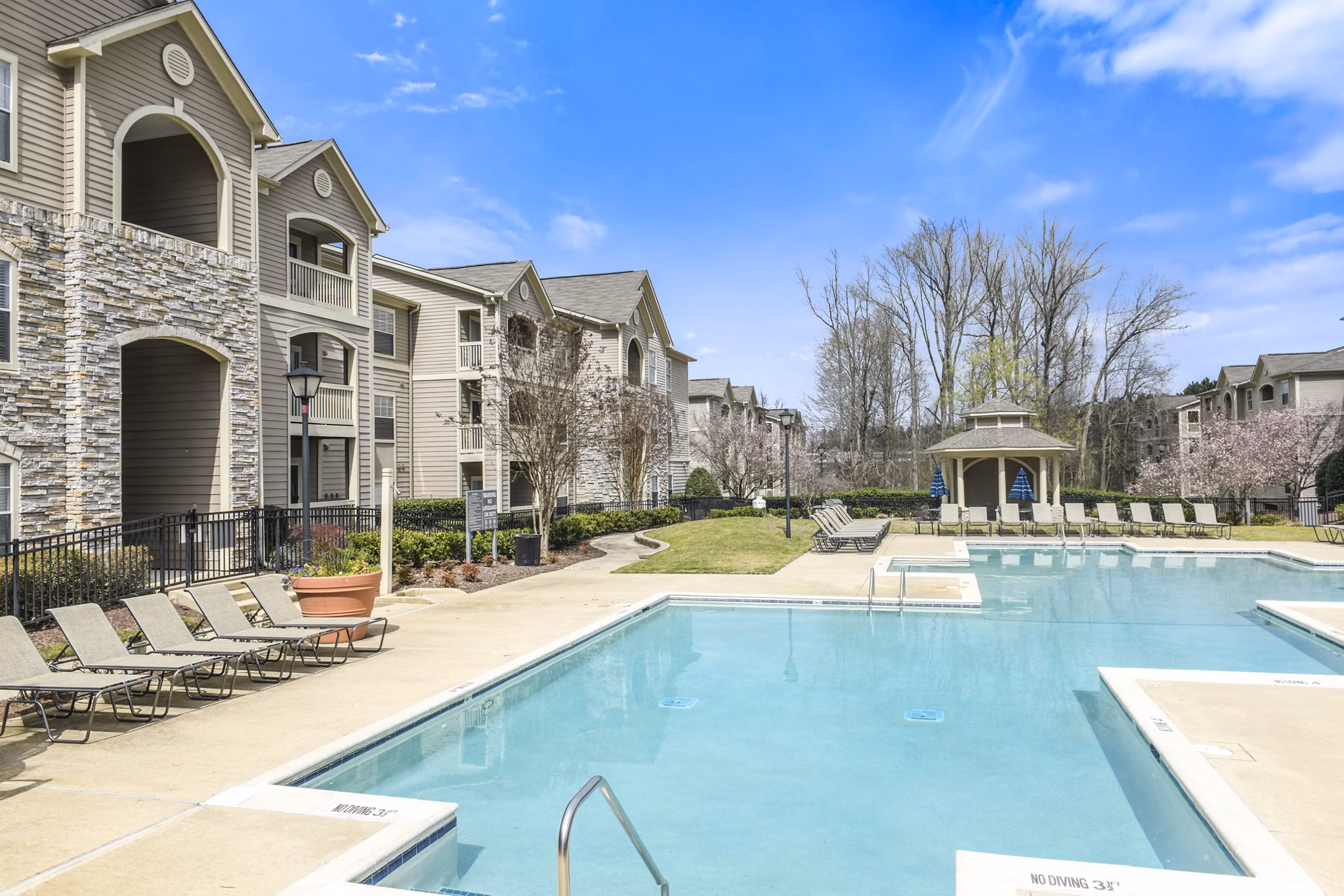 Outdoor swimming pool area with lounge chairs and luxury apartments in the background