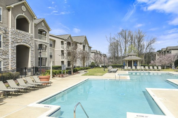 Outdoor swimming pool area with lounge chairs and luxury apartments in the background