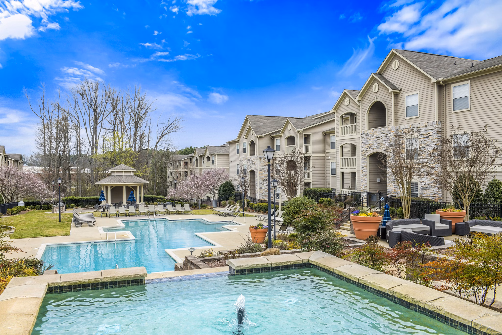 Luxury apartment complex featuring a swimming pool, lounge chairs, and landscaped gardens