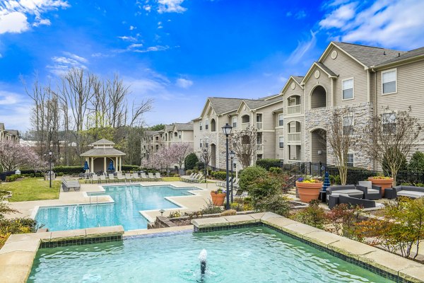 Luxury apartment complex featuring a swimming pool, lounge chairs, and landscaped gardens