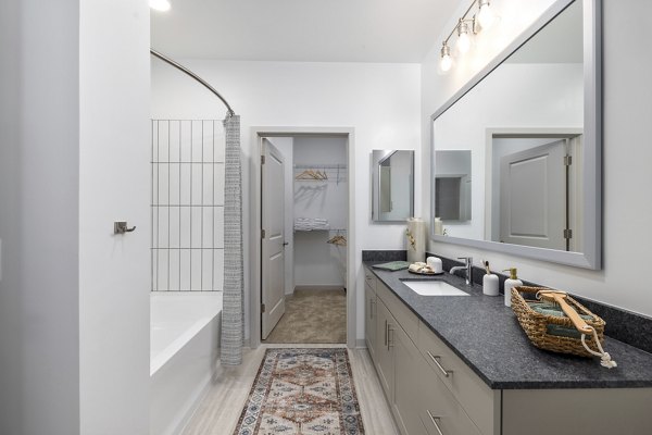 Modern bathroom featuring walk-in shower and double vanity at Overture Tributary Apartments