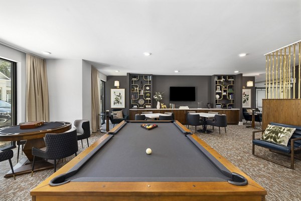Modern game room with billiards table and lounge chairs at Overture Tributary Apartments