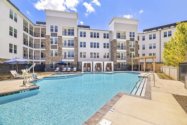 Resort-style pool at Overture Tributary Apartments with lush landscaping and ample lounge chairs