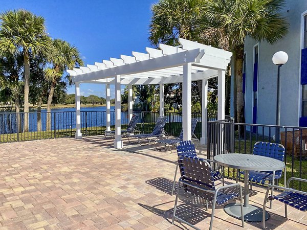 Sunlit pool patio at Cielo Point Apartments featuring comfortable lounge chairs and lush greenery
