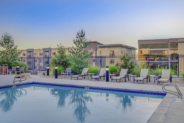 Outdoor swimming pool with lounge chairs at The Calo Apartments, offering luxurious relaxation in a vibrant setting