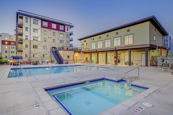 Rooftop pool with lounge chairs overlooking skyline at The Calo Apartments