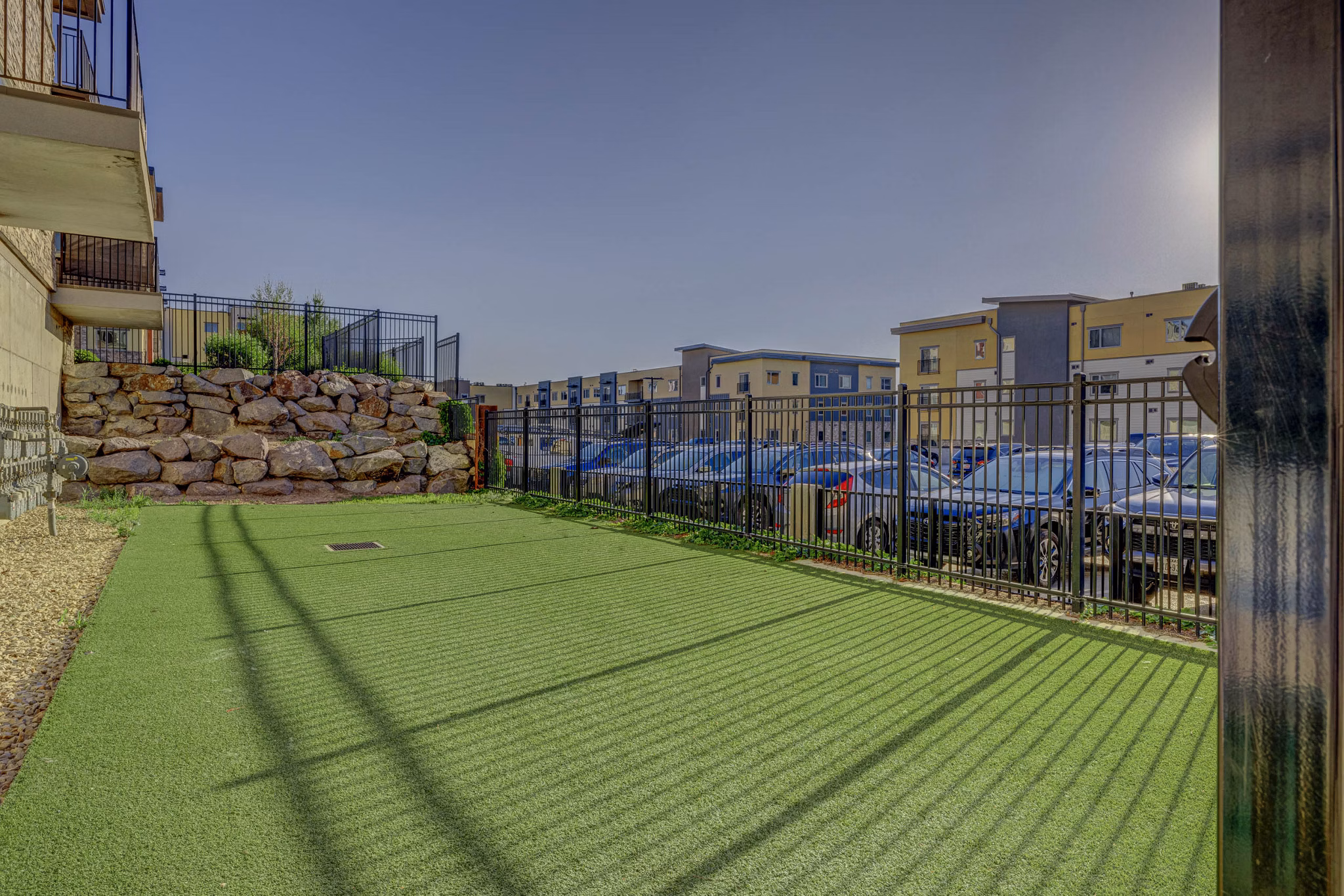 Leash-free dog park at The Calo Apartments featuring agility equipment and shaded seating areas