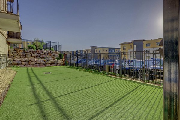 Leash-free dog park at The Calo Apartments featuring agility equipment and shaded seating areas
