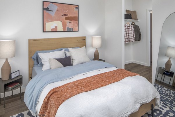 Cozy bedroom with modern decor and large windows at The Overland Apartments