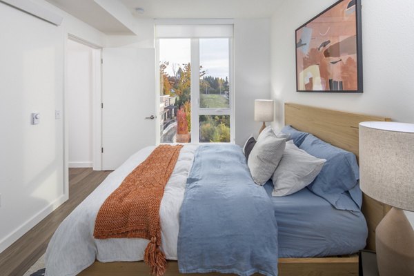 Cozy bedroom featuring large windows and modern decor at The Overland Apartments