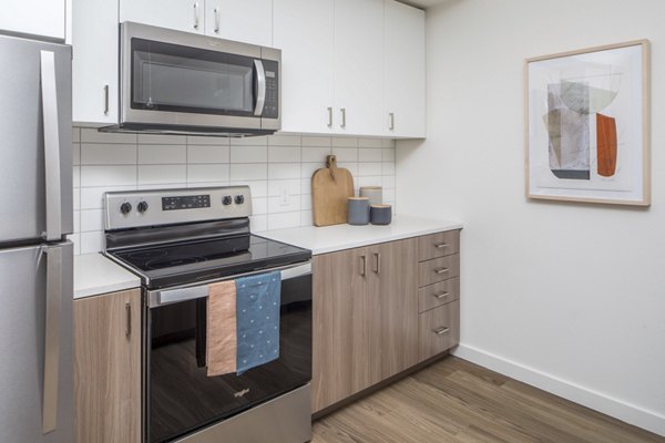 Modern kitchen with stainless steel appliances at The Overland Apartments, featuring sleek cabinetry and a spacious design for luxury living