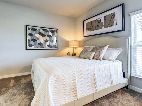 Cozy bedroom with stylish design at Sereno Apartments, featuring plush bedding and natural light for ultimate comfort
