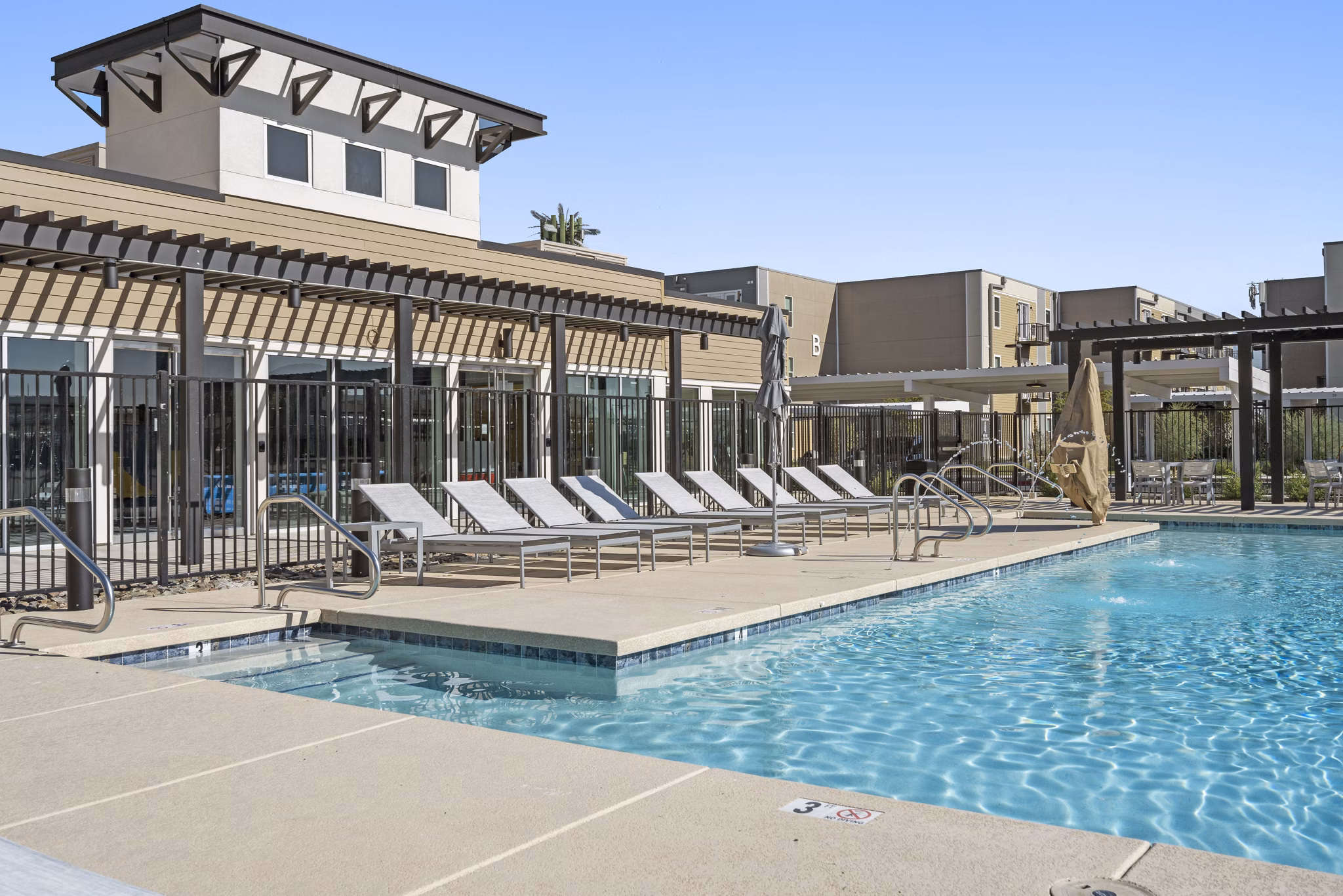 Resort-style pool with lounging area at FLATZ 602 Apartments