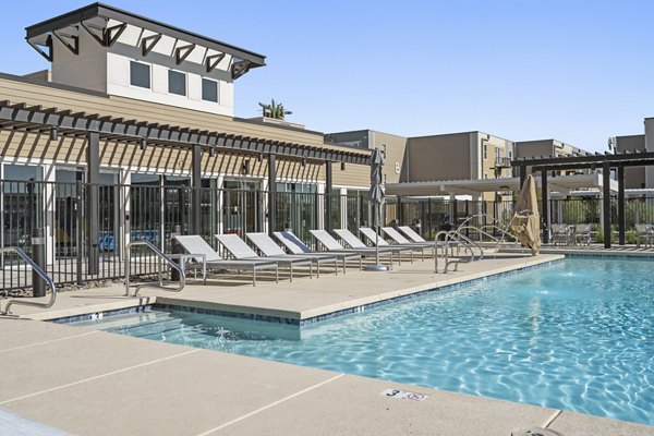 Resort-style pool with lounging area at FLATZ 602 Apartments