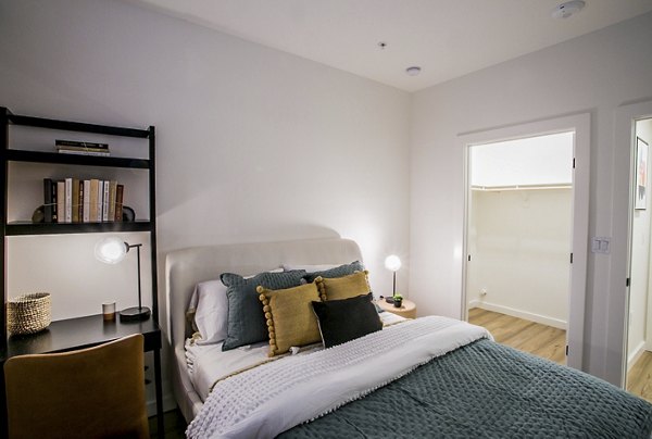 Modern bedroom with stylish decor at Alma Apartments, featuring a cozy bed and large window offering natural light
