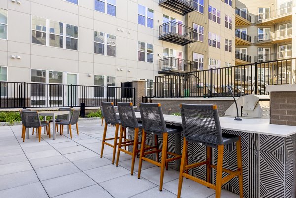 Outdoor grill area at The Cynwyd Apartments featuring modern barbecue stations and seating, perfect for social gatherings and enjoying open-air cooking