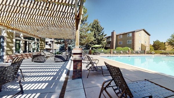 Modern outdoor pool at Glen at the Park Apartments with sun loungers and lush landscaping, ideal for relaxation and recreation