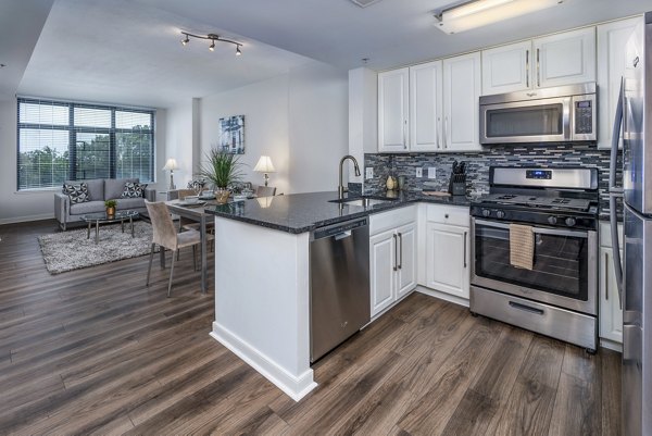 Modern kitchen with granite countertops and stainless steel appliances at The Barton at Woodley Apartments