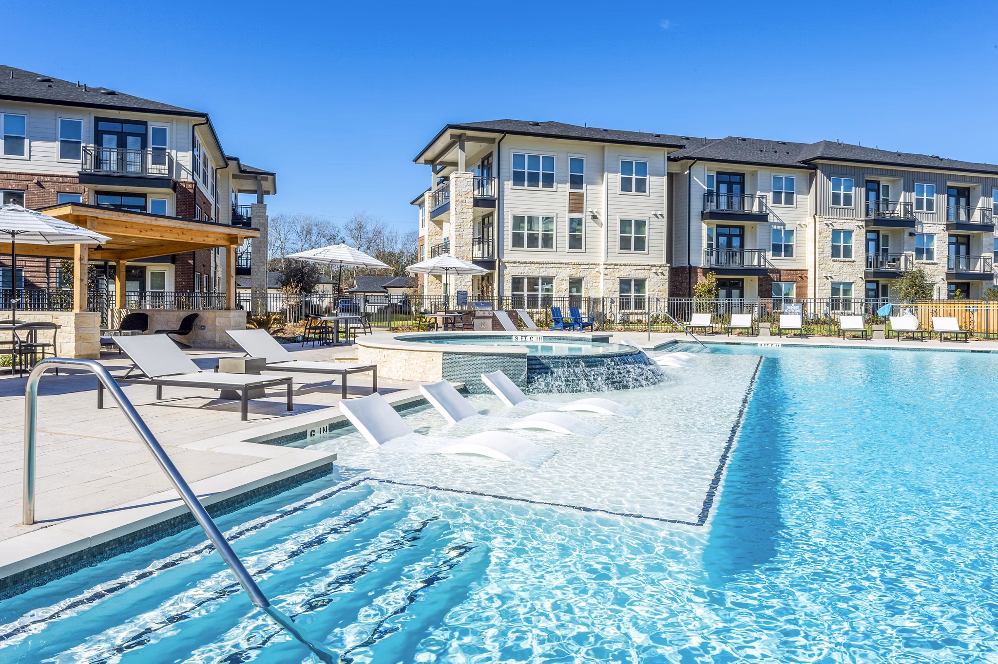 Relax by the infinity pool at The Waterview Apartments, featuring luxurious poolside seating and stunning water views