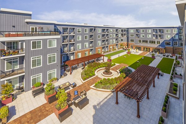 Tranquil courtyard patio at Icon Riverwalk Apartments, featuring lush greenery and cozy seating for relaxation