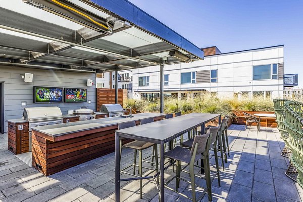Outdoor patio with modern grill area at Mason & Main Apartments, offering a relaxing space for residents
