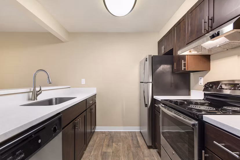 Modern kitchen featuring stainless steel appliances and granite countertops at The Fairways Apartments