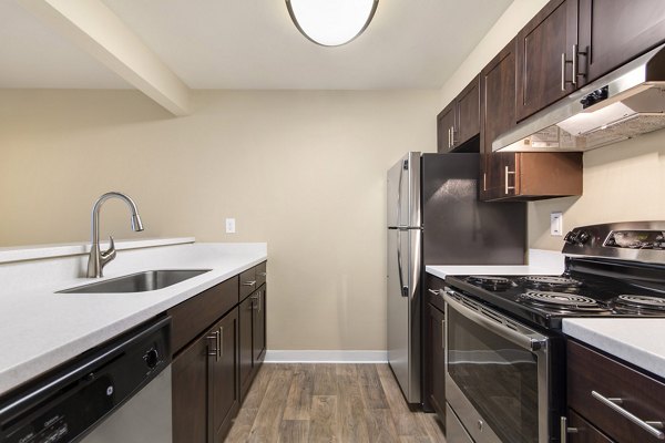 Modern kitchen featuring stainless steel appliances and granite countertops at The Fairways Apartments