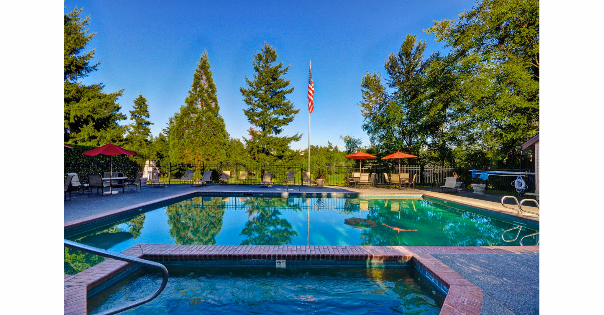 Luxurious outdoor pool area at The Fairways Apartments with sun loungers and lush greenery, perfect for relaxation and leisure activities