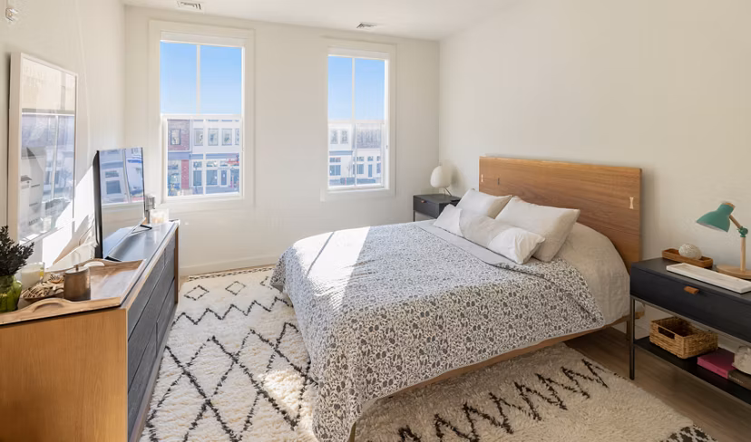 Bedroom featuring stylish bedding and ample natural light at Darien Commons Apartments