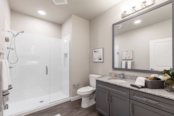 Bathroom featuring sleek fixtures and marble countertops in Avenida at Centerra Apartments