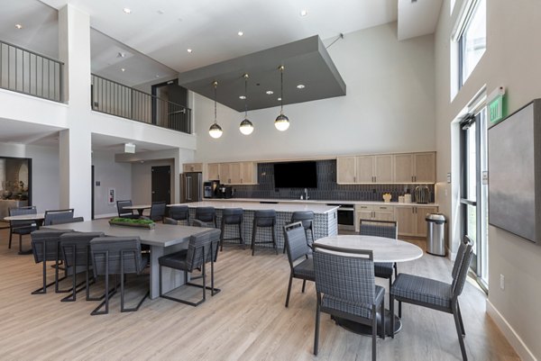 Avenida at Centerra Apartments: Modern clubhouse featuring stylish seating and a fireplace in a luxury setting