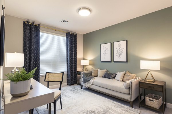 Home office featuring modern desk and cozy seating in Avenida at Centerra Apartments Ideal for remote work with ample natural light