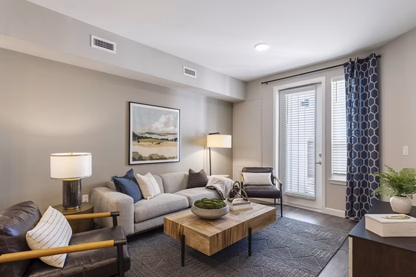 Living room with modern decor at Avenida at Centerra Apartments, featuring comfortable seating and large windows