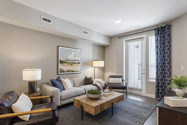 Living room with modern decor at Avenida at Centerra Apartments, featuring comfortable seating and large windows