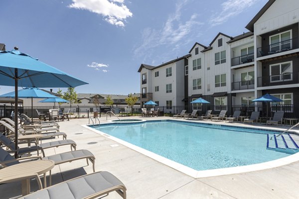 Relaxing pool area with seating and landscaping at Avenida at Centerra Apartments, perfect for luxury living and outdoor enjoyment