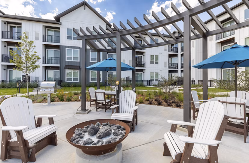 Fire pit area with cozy seating at Avenida at Centerra Apartments, perfect for relaxation and social gatherings in a luxurious setting