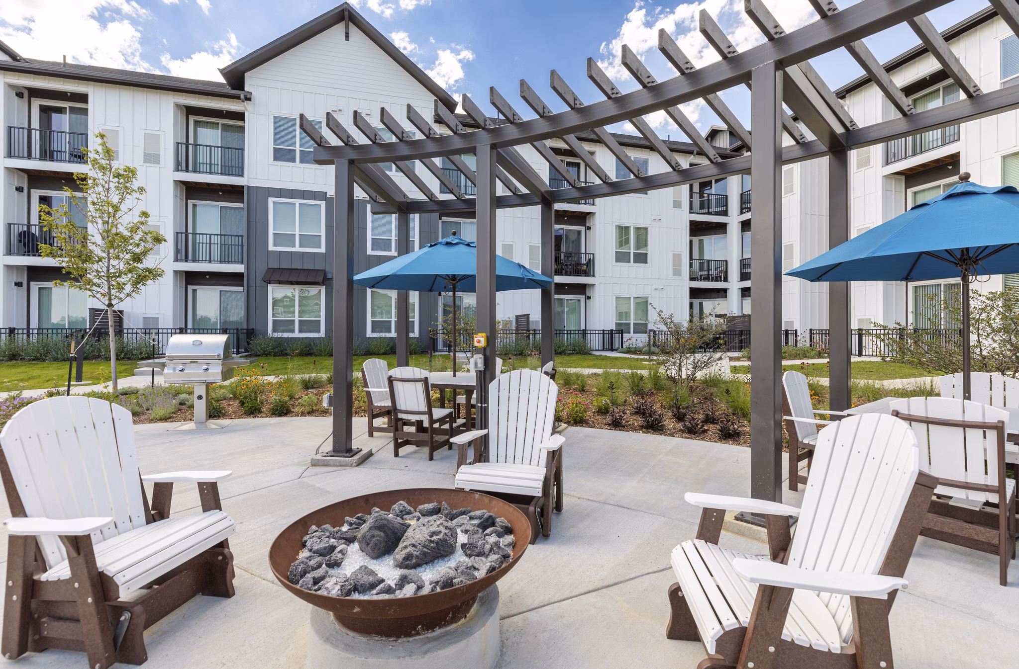 Fire pit area with cozy seating at Avenida at Centerra Apartments, perfect for relaxation and social gatherings in a luxurious setting