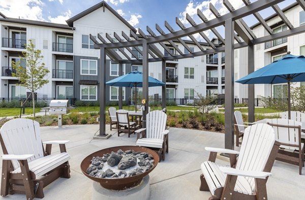 Fire pit area with cozy seating at Avenida at Centerra Apartments, perfect for relaxation and social gatherings in a luxurious setting
