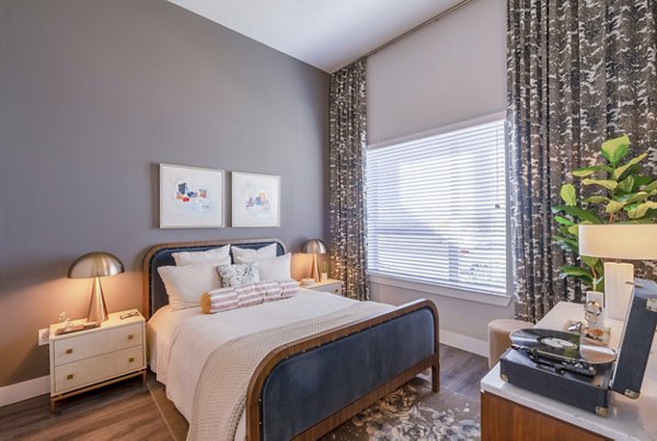 Bedroom with modern furnishings and large windows at Cadence at Frisco Station Apartments, a Greystar luxury community