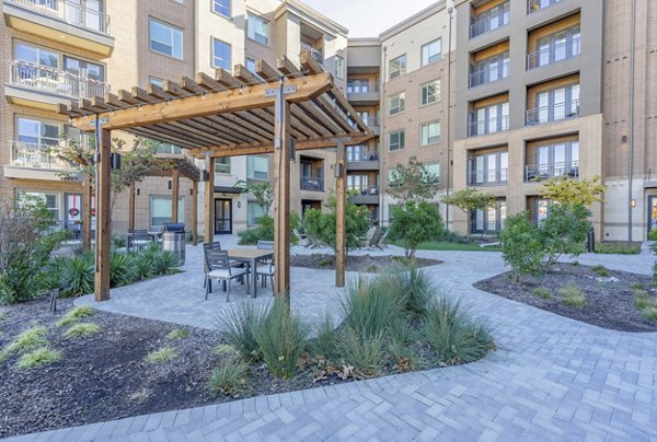 Courtyard featuring landscaped gardens and seating at Cadence at Frisco Station Apartments