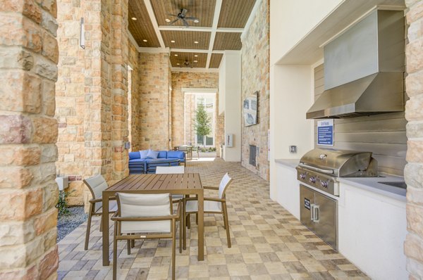 Grill area with modern outdoor seating at The Link at Twin Creeks Apartments, a luxury community offering premier amenities for residents