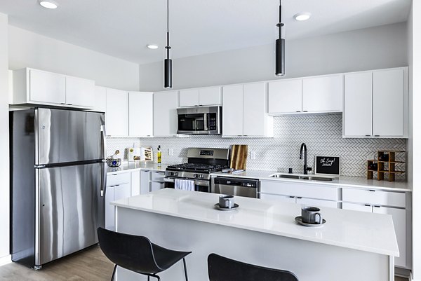Modern kitchen layout with stainless steel appliances at Beyond Woodbury Apartments, offering luxury living spaces for residents
