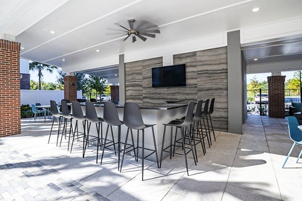 Outdoor pool patio at The Accolade Collegiate Village West Apartments with modern lounge chairs and lush landscaping