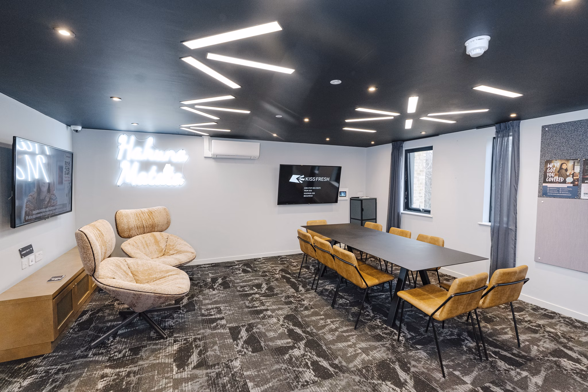 Stylish communal lounge at Chapter Westminster with cozy seating, a large TV, and elegant lighting.