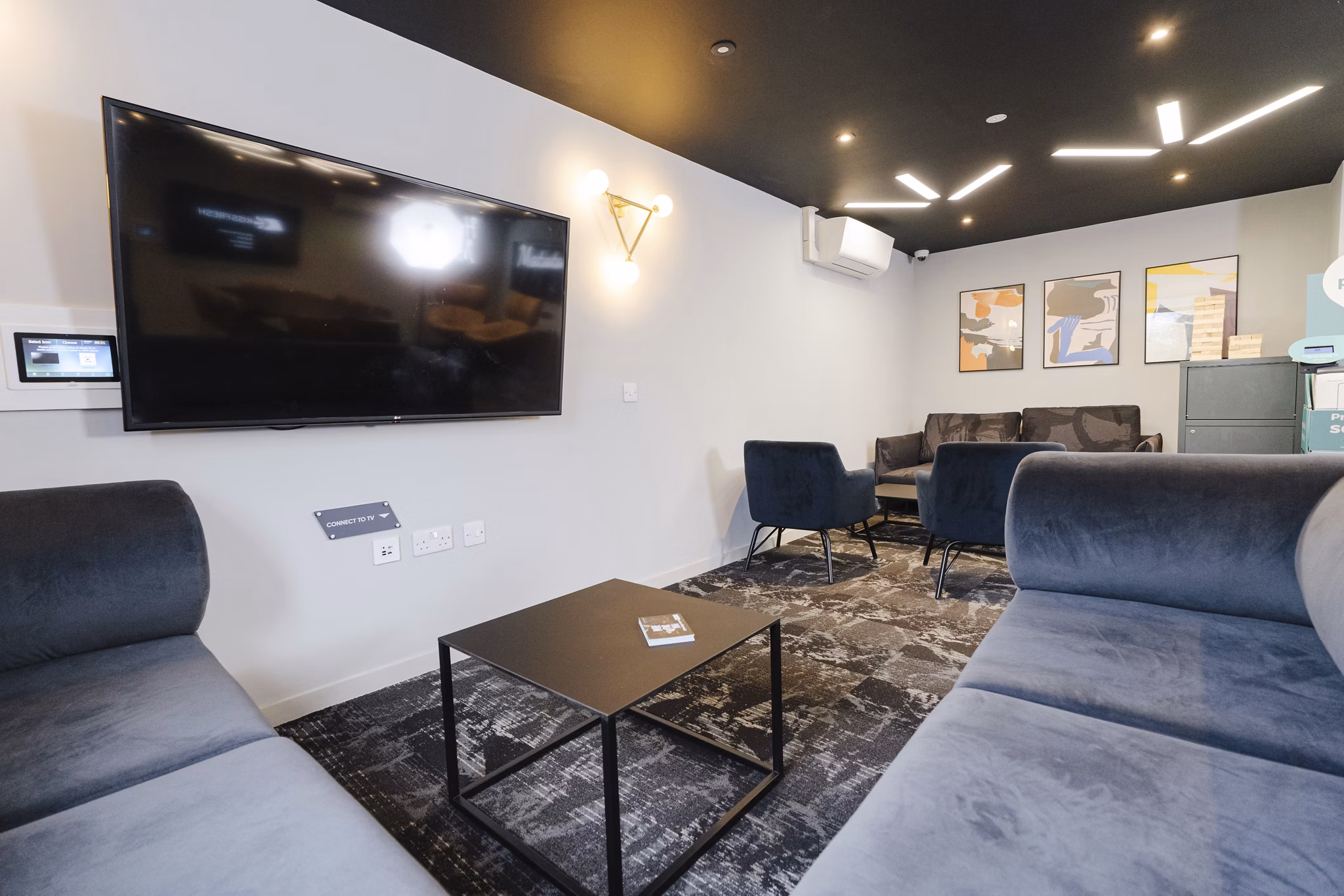 Comfortable and modern communal area at Chapter Westminster with a large screen and relaxed seating.