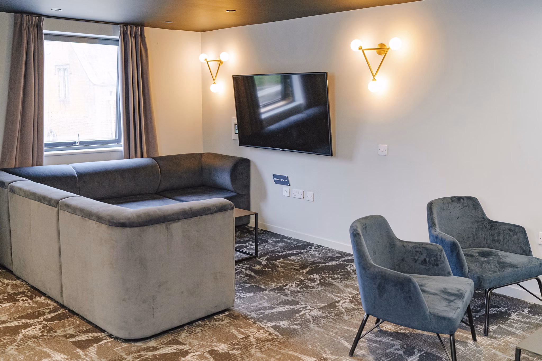 Cozy corner lounge at Chapter Westminster with a sectional sofa, armchairs, and soft lighting.