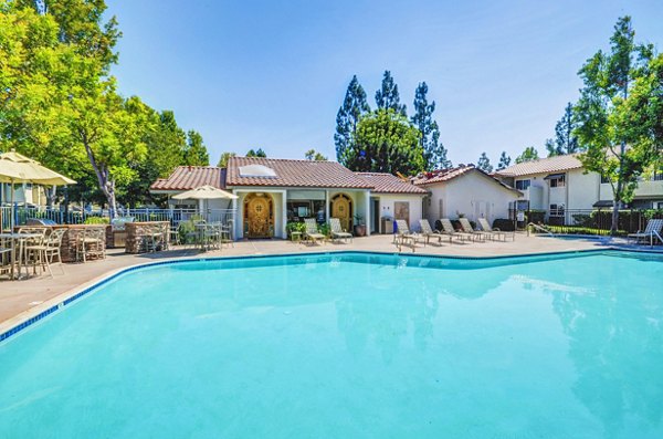 Resort-style pool at Adagio Apartments featuring lounge chairs and palm trees