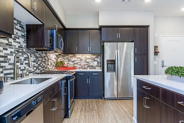 Modern kitchen featuring granite countertops and stainless steel appliances at Altura Apartments