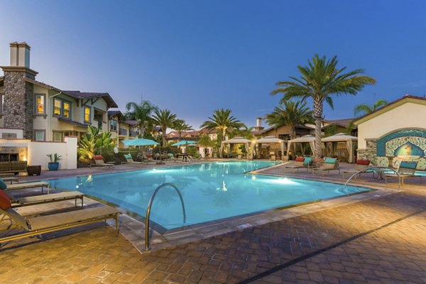 Olympic-sized pool with lounge chairs at Avino Apartments in scenic setting